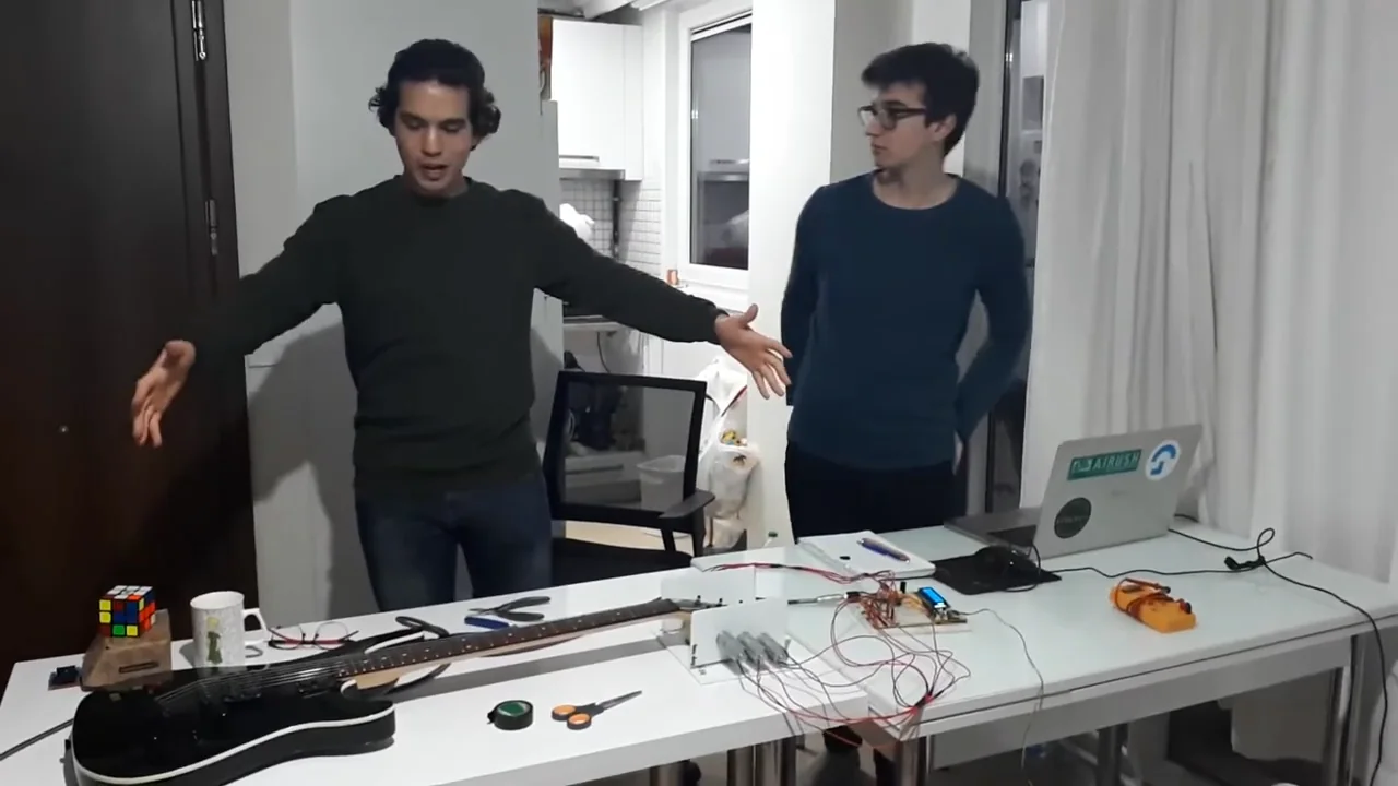Sina and Abdullah standing behind their guitar tuner with DC motors.